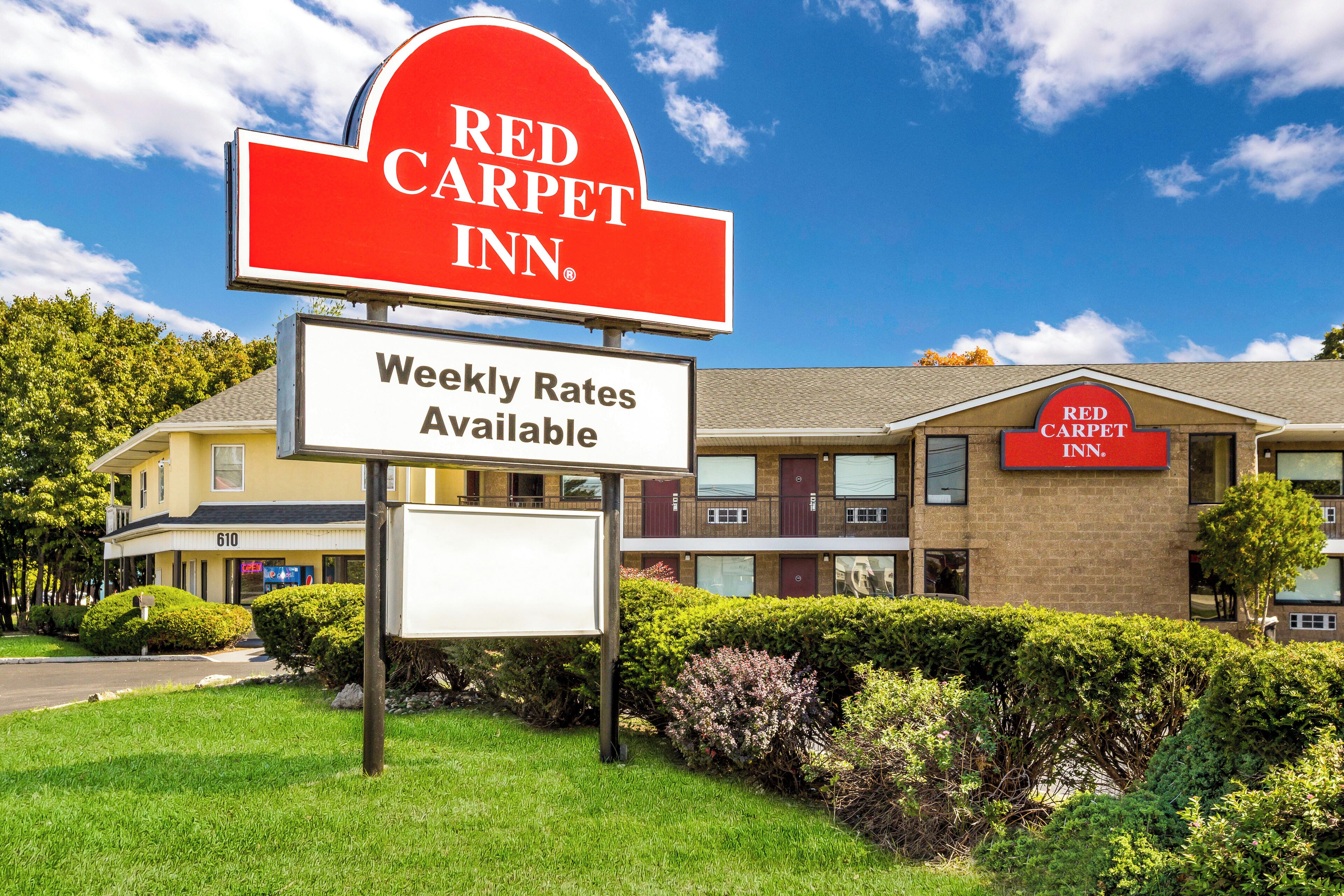 A Red Carpet Inn sign with a weekly rates sign below it.