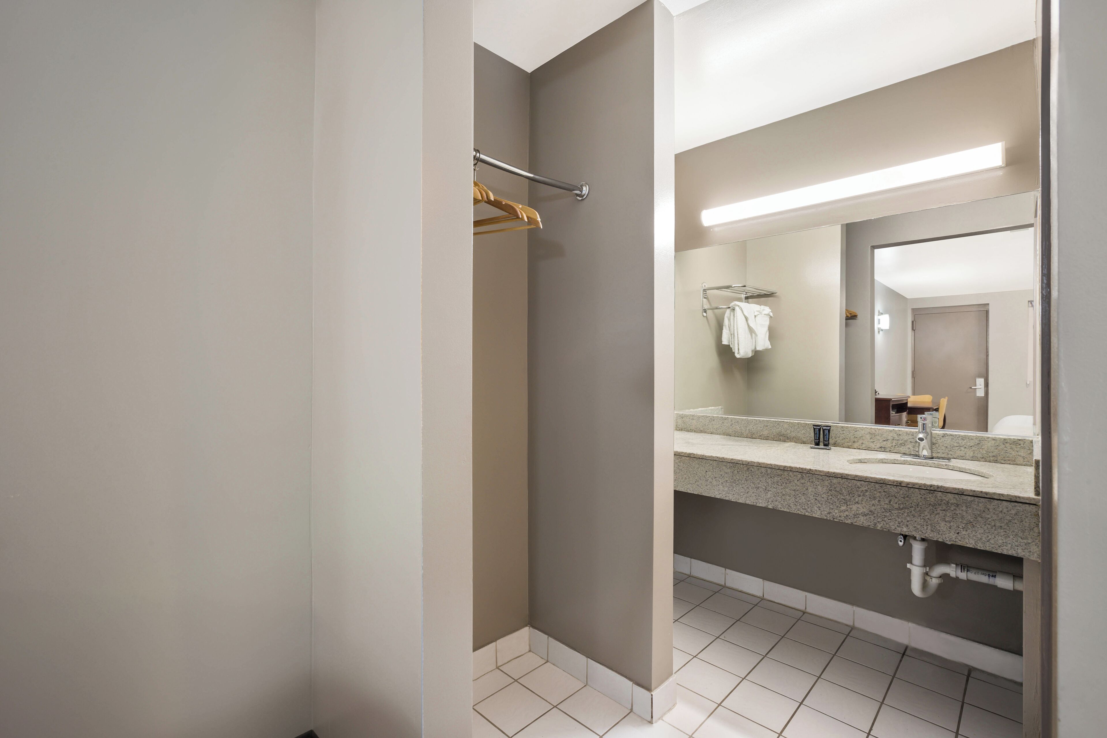 A modern bathroom with a large mirror, a towel rack, and a sink.