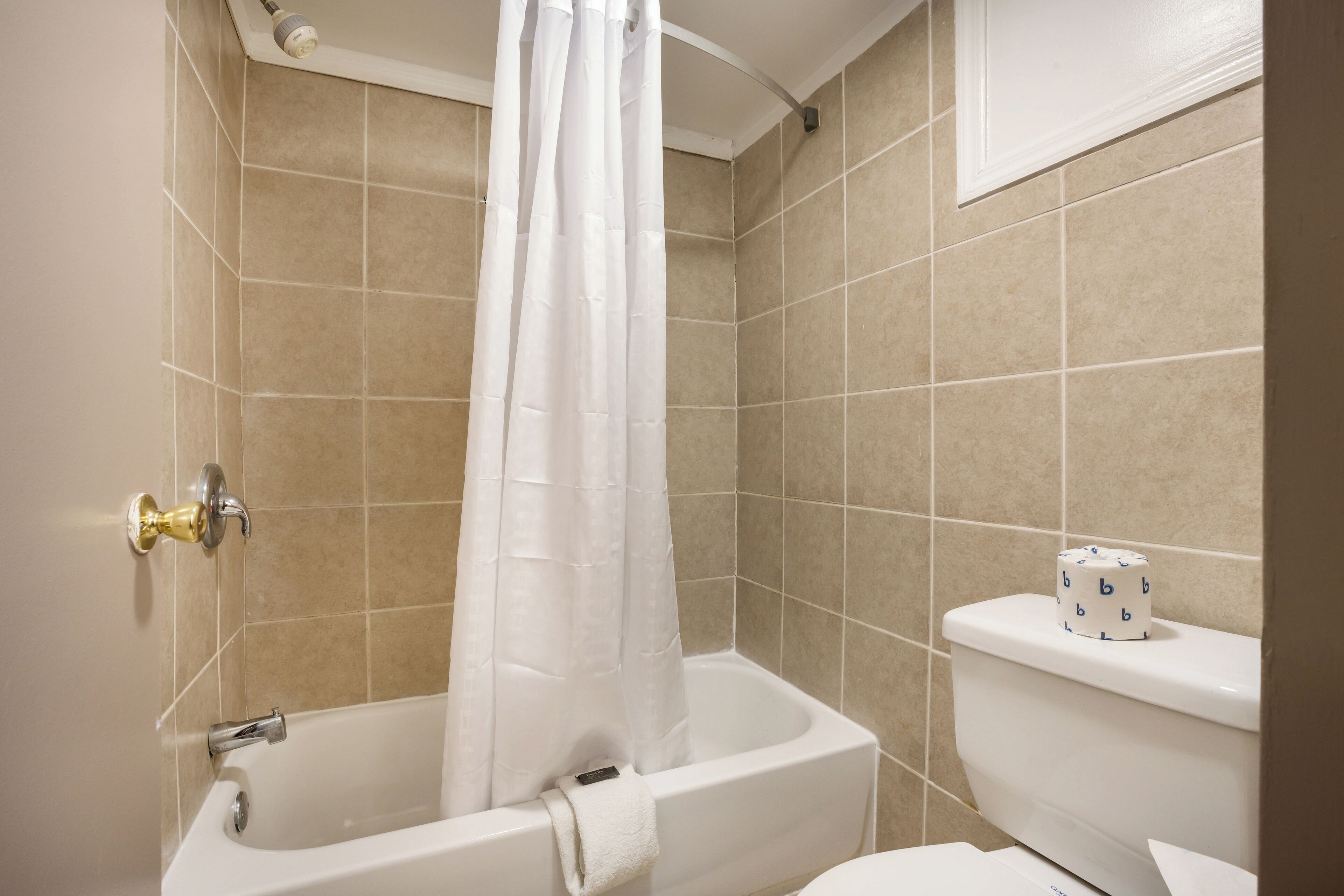 A bathroom with a bathtub, toilet, and shower curtain.