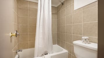 A bathroom with a bathtub, toilet, and shower curtain.