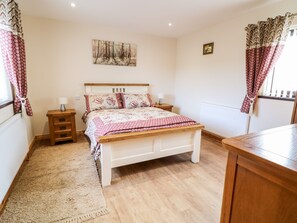Quarto com cama de madeira, mesas de cabeceira, tapete e cortinas.