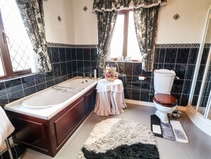 Ein Badezimmer mit Badewanne, Toilette und einem kleinen Tisch mit einem Blumenkorb.