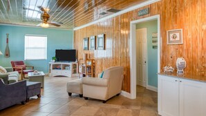 A living room with a television, two sofas, a coffee table, and a wooden accent wall. - Windswept Beach House (St. Augustine)