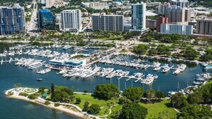 An aerial view of a marina with numerous boats docked, surrounded by high-rise buildings and greenery. - Beach Cottage with a Private Hot Tub (Longboat Key)