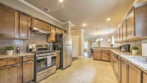 Une cuisine moderne avec des meubles en bois, des appareils électroménagers en acier inoxydable et un sol en marbre.