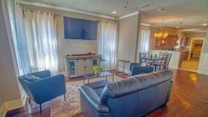 Un salon moderne avec un canapé en cuir foncé, une table basse et un téléviseur fixé au mur.