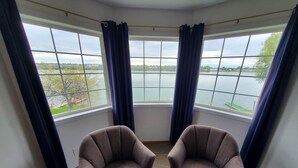 Een hoekzaak met twee fauteuils gericht op een groot raam met uitzicht op een meer.