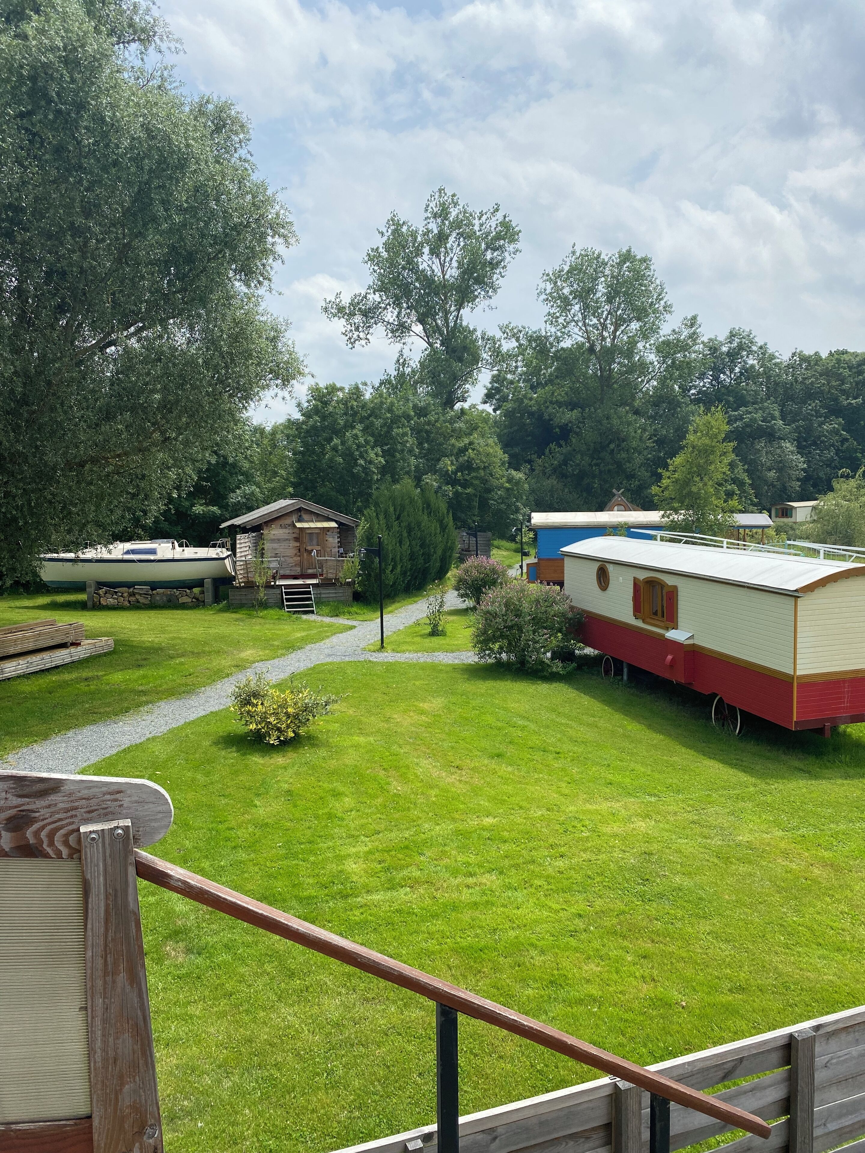A campsite with a grassy lawn, a wooden deck, and a row of mobile homes.