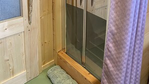 Ett rum med träpanel, en glasdörr, ett metallhandtag och en lila gardin.