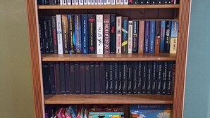 Ein Bücherregal aus Holz mit mehreren Regalböden, gefüllt mit Büchern.