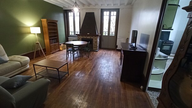 Ein Wohnzimmer mit einer Couch, einem Couchtisch, einem Kamin, einem Fernseher und einer Küchenzeile mit einem Herd.