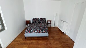 Ein Schlafzimmer mit einem Bett, zwei Nachttischen, einer Stehlampe und einer Heizung.