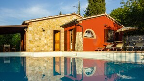 Un edificio in pietra con piscina, porte in legno e facciata rossa.