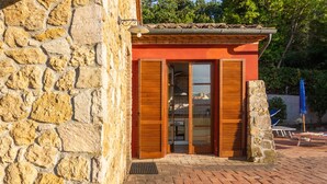 Un edificio in pietra con patio in mattoni, persiane in legno e tetto in tegole.