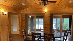 A wooden interior with a dining area, ceiling fan, and large windows overlooking a body of water. - Large House with Front Row View of the Cliffs (Edgemont)
