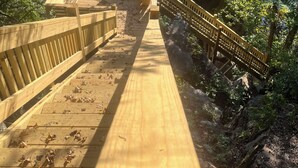 A wooden boardwalk leading to a wooden viewing platform with benches, overlooking a body of water and rocky cliffs. - Large House with Front Row View of the Cliffs (Edgemont)