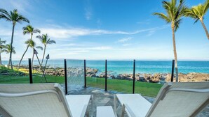 A patio with two white lounge chairs facing a rocky coastline and the ocean. - 308 – Deluxe Oceanfront One Bedroom Unit with A/C! (Kihei)