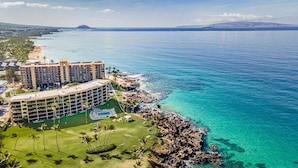 A resort with a large building, a pool, and a view of the ocean. - 308 – Deluxe Oceanfront One Bedroom Unit with A/C! (Kihei)