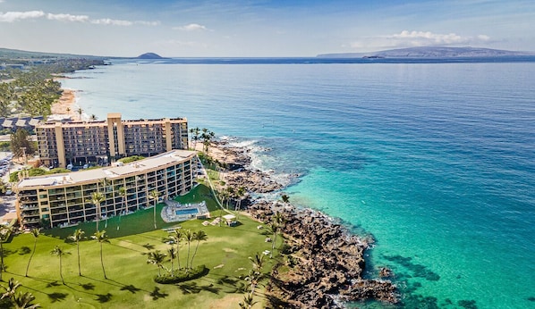 A resort with a large building, a pool, and a view of the ocean.