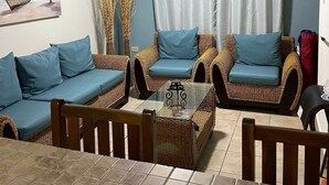 A living room with wicker furniture, a ceiling fan, a painting of a beach scene, and a view of the ocean through a window. - NEW! Walking distance to Boqueron ‘Poblado’, townhouse w/amazing views, sleeps 8 (Boqueron)