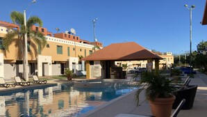 A swimming pool with lounge chairs, a covered seating area, and a building with balconies and satellite dishes. - NEW! Walking distance to Boqueron ‘Poblado’, townhouse w/amazing views, sleeps 8 (Boqueron)