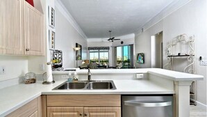 Una cocina moderna con un lavabo doble, armarios de madera y lavavajillas.