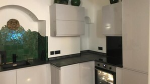 A modern kitchen with white cabinetry, a black countertop, and a built-in oven. - Apartment (nice)