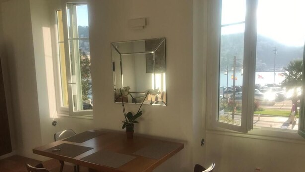 A dining area with a wooden table and two chairs, a potted plant, and a large mirror on the wall. - Apartment (nice)