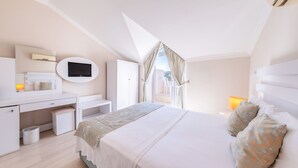 A bedroom with a bed, desk, TV, and a balcony view. - Sahra Su Holiday Village & SPA (Fethiye)