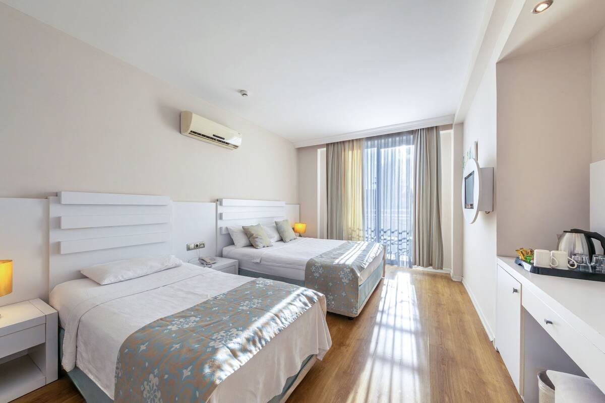Une chambre d’hôtel avec deux lits, un bureau avec une bouilloire et une télévision.