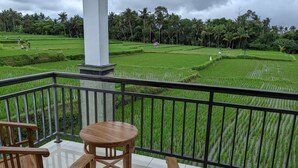 A balcony with a view of lush green rice fields and palm trees under a cloudy sky. - Just outside Ubud, peaceful 3BR Villa with rice field views. (Tampaksiring, Gianyar Regency)