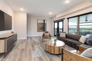 A modern living room with a wooden coffee table, leather sofa, and a TV mounted on the wall. - 10-Bedroom Lakeside Lodge with Indoor Pool, Sleeps 34, Near Table Rock Lake (Hollister)