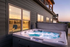 A hot tub outside a building with large windows.
