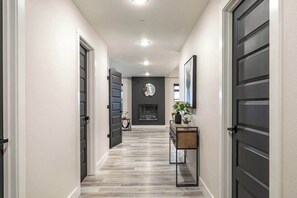 A hallway with a fireplace, a console table, and a door on the right.