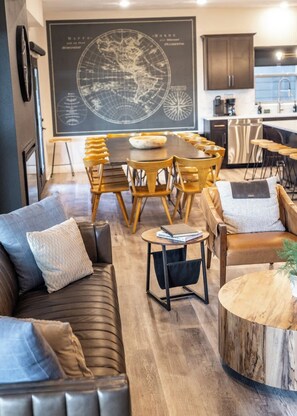 A modern living room with a leather sofa, a round wooden coffee table, and a dining area with a wooden table and chairs.