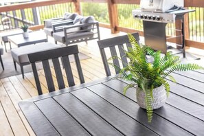 A wooden deck with outdoor furniture, including a table and chairs, and a grill. - 10-Bedroom Lakeside Lodge with Indoor Pool, Sleeps 34, Near Table Rock Lake (Hollister)