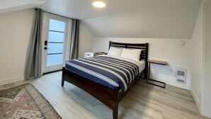 A bedroom with a bed, a window, and a ceiling light. - Salt Loft - Oceanfront, Hot Tub and Firepit! (Ucluelet)