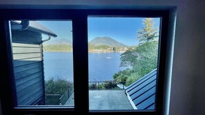 A view from a window overlooking a lake with mountains in the background. - Salt Loft - Oceanfront, Hot Tub and Firepit! (Ucluelet)