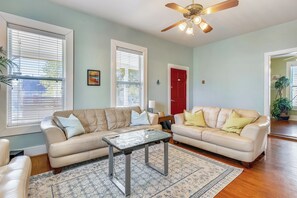 A living room with two beige leather sofas, a glass coffee table, and a patterned rug.