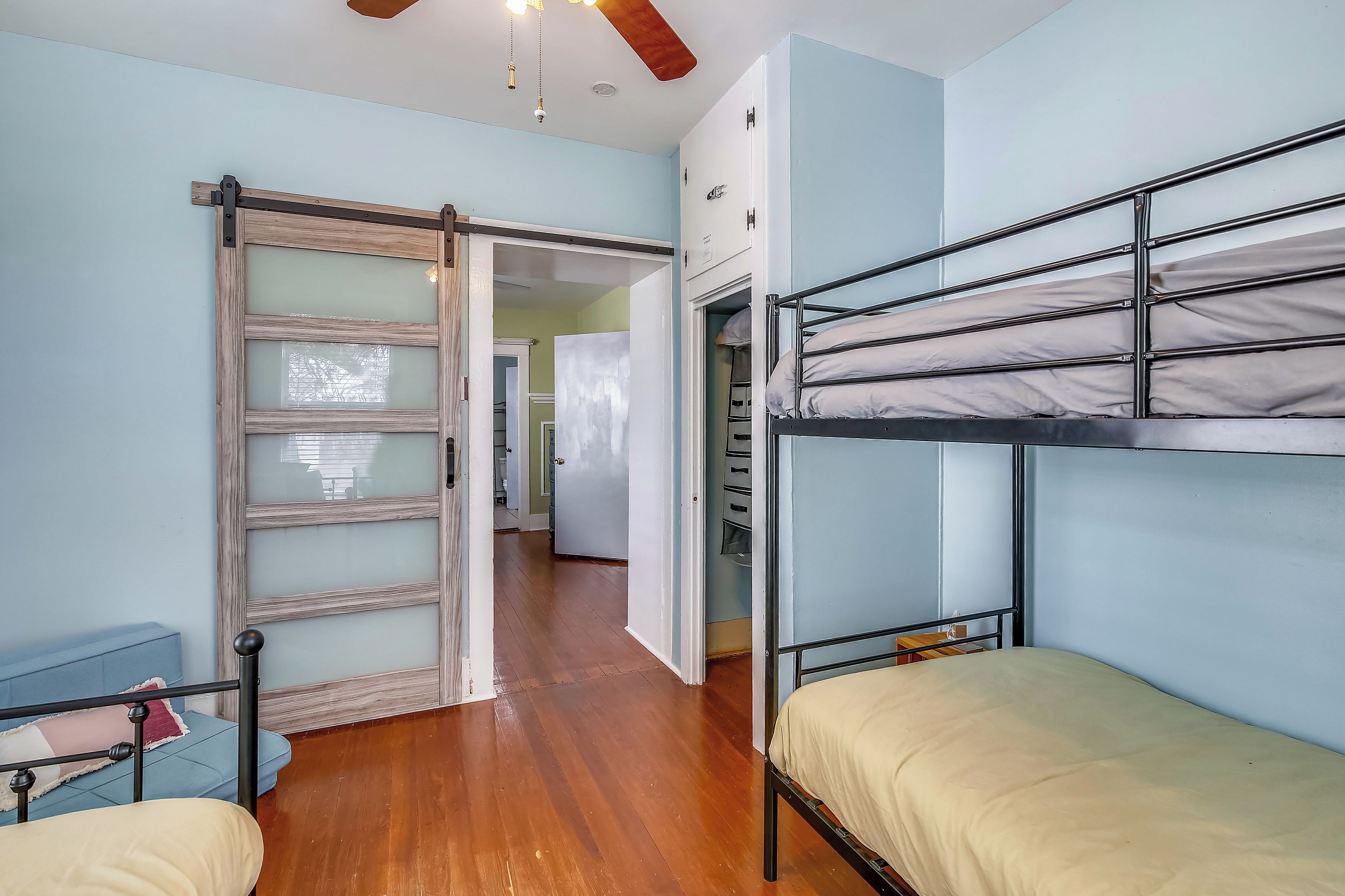 A room with bunk beds, a sliding door, a wardrobe, and a ceiling fan.