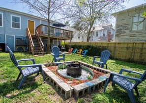 A backyard with a fire pit, outdoor furniture, and a deck.