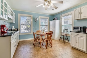 A kitchen with a dining table, chairs, a ceiling fan, and a microwave.