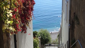 Un escalier en pierre menant à une plage d’où l’on a une vue sur la mer.