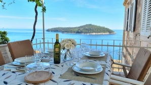 Une table dressée pour le dîner, avec vue sur la mer et une île en arrière-plan.