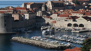 Une ville côtière dotée d’une architecture historique, d’un rempart et d’un port de plaisance où sont amarrés des bateaux.