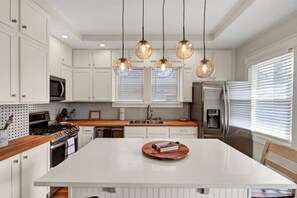 Modern kitchen with central island, white cabinetry, and stainless steel appliances.