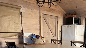A kitchen with a wooden island, two bar stools, a refrigerator, and a microwave on top of the fridge. - Cooperstown Lake Cabin Million Dollar Views (Cooperstown)