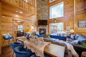 L’intérieur d’une cabane en rondins, avec une cheminée en pierre, des murs en bois et un coin salon confortable.