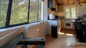A modern kitchen with large windows, a dining area, and a seating bench. - Loft at the foot of the Ventoux with swimming pool, jacuzzi and balneotherapy. (Mollans-sur-Ouvèze)
