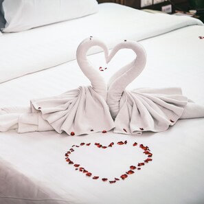 Una cama con una decoración de toallas en forma de dos cisnes y un corazón hecho de pétalos de rosa.